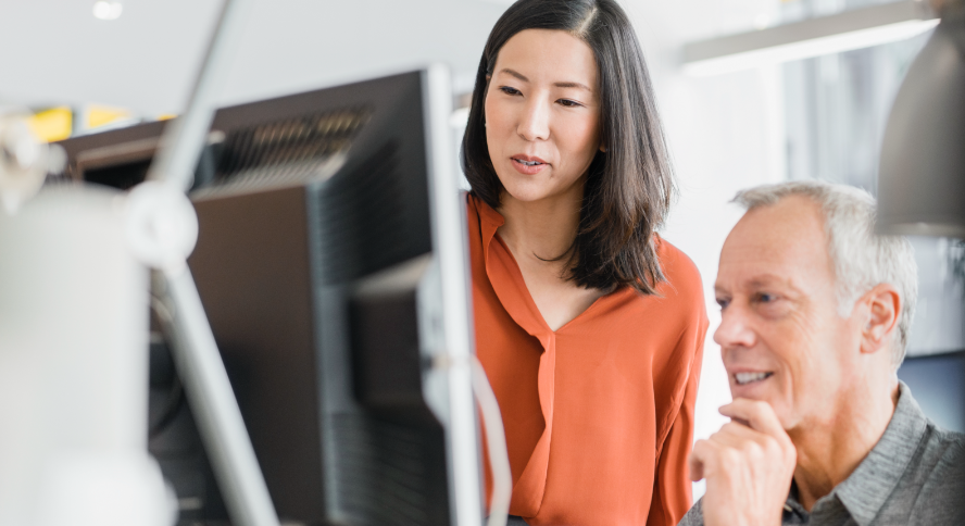 A man and woman facing a computer screen